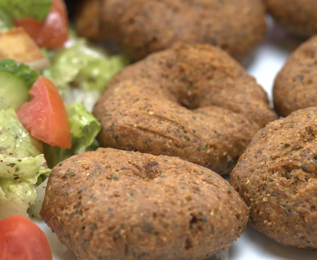 Crisp golden-brown falafel patties with lettuce, tomato, and cucumber salad