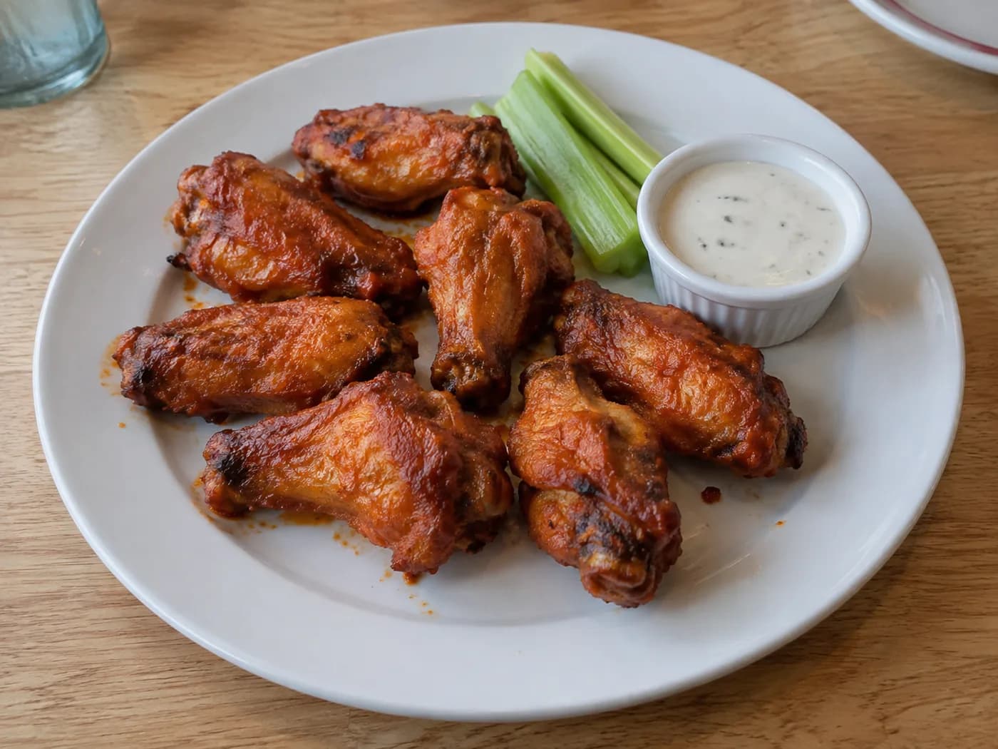 Plate of glazed chicken wings with dipping sauce